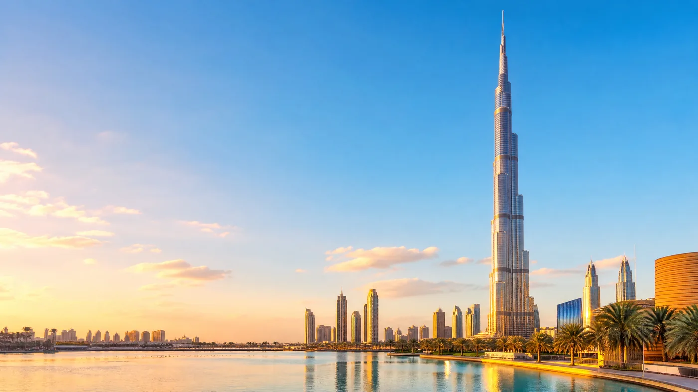 Der Burj Khalifa jenseits des ruhigen Burj Lake zur goldenen Stunde, Palmen und niedrige Gebäude zu seinen Füßen