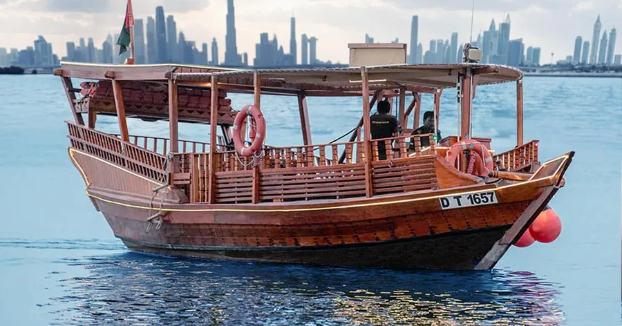 Eine traditionelle hölzerne Abra auf dem Burj Lake mit der Skyline von Downtown dahinter