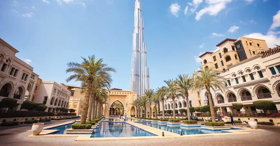 Der Burj Khalifa hinter den Arkaden, Palmen und dem Pool des Souk Al Bahar